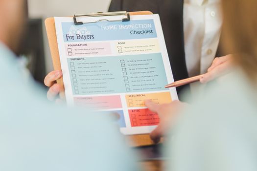 Close-up of hands holding a home inspection checklist clipboard for buyers.